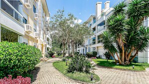 Un immeuble résidentiel doté de nombreux balcons, d’un chemin pavé et de diverses plantes.