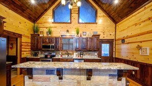 A kitchen with wooden walls, a stone island, and dark wooden cabinets.