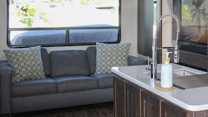 A compact kitchenette with a built-in sink, a small countertop, and a window above the sink.