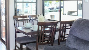 A dining area with a table set for four, surrounded by wooden chairs.