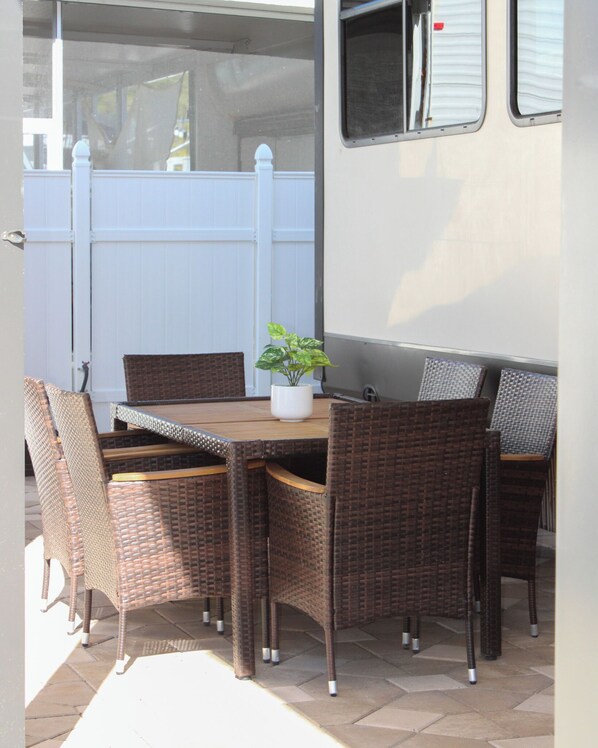 An outdoor patio with wicker furniture, a table, and chairs.