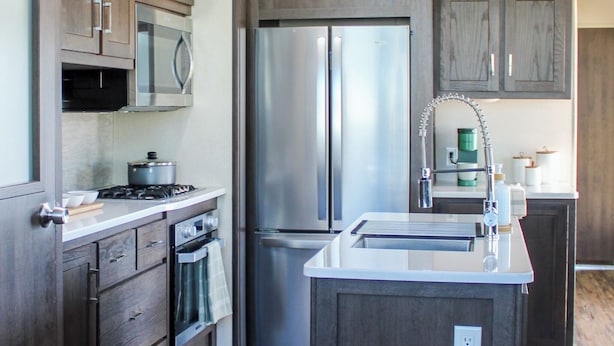 A modern kitchen with dark wood cabinets, stainless steel appliances, and a central island.