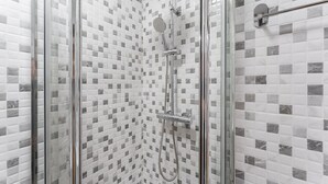 Une douche avec une porte en verre et un mur carrelé orné d’un motif à carreaux.