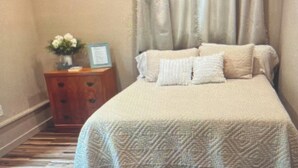 Une chambre à coucher avec un lit, une table de chevet et un vase de fleurs.