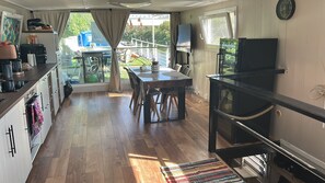 Una cocina con comedor, televisión y vistas al exterior.