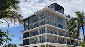 Un immeuble à plusieurs étages, doté de balcons et de grandes fenêtres, entouré de palmiers.