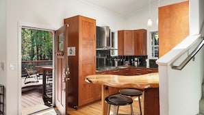 Een moderne keuken met houten kastjes, een roestvrijstalen fornuis en een houten bar met krukken.