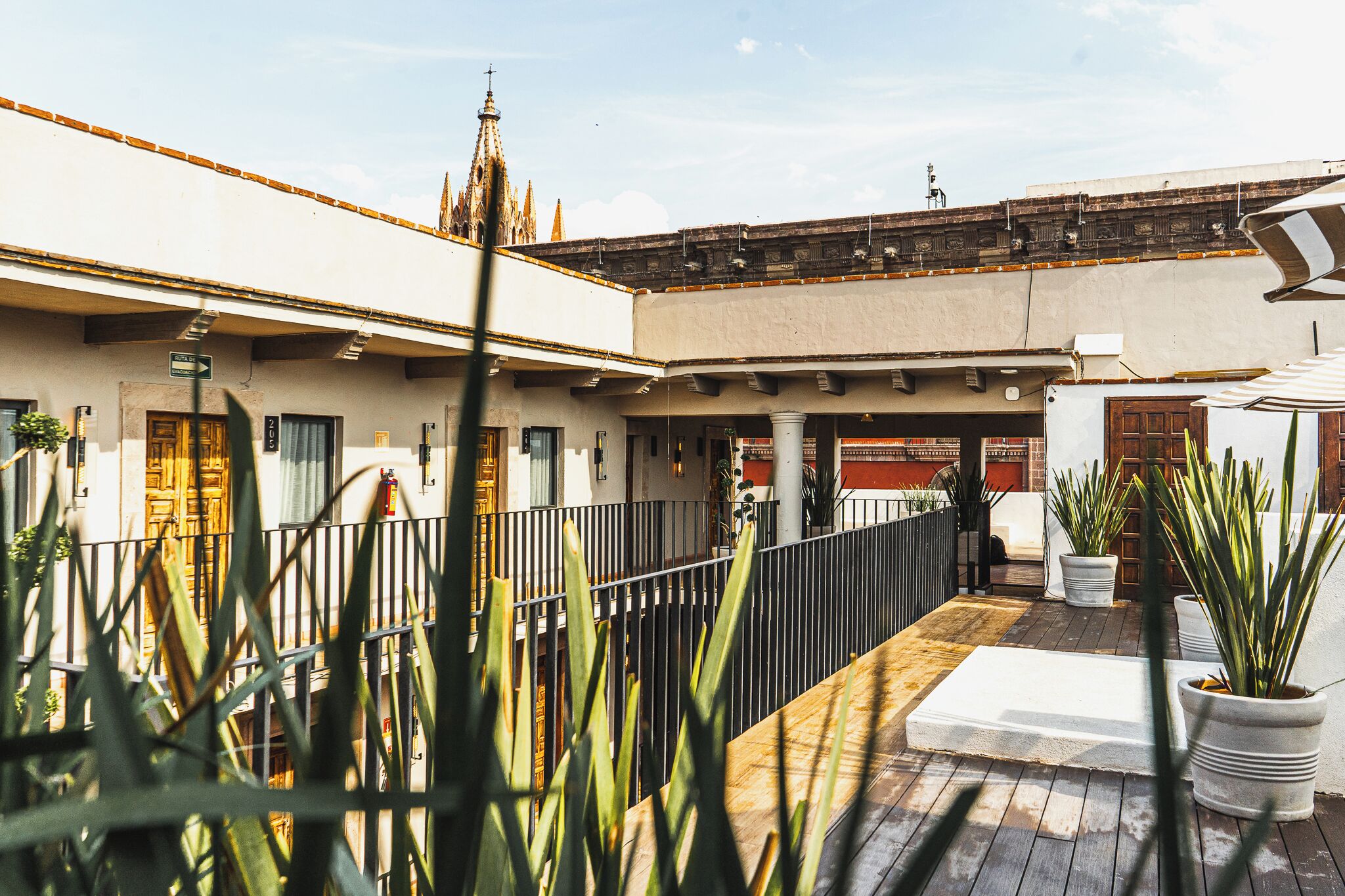 A courtyard with a wooden deck, potted plants, and a building with a traditional facade and a tower.