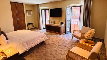 A hotel room with a bed, a desk, a chair, a TV, and a balcony with a view.