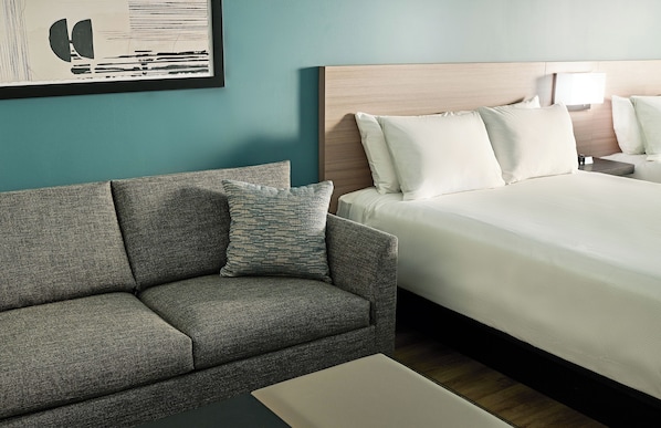 A hotel room with a bed, a sofa, a nightstand, a lamp, and a framed picture on the wall. - Hyatt Select Boston/Woburn/Burlington (Woburn)