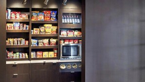 Una cocina con estantes llenos de refrigerios, un microondas y una estufa.