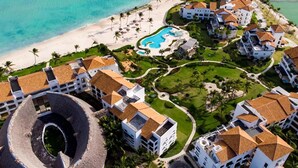 Vista aérea de un complejo turístico con varias edificaciones, una piscina y una playa.