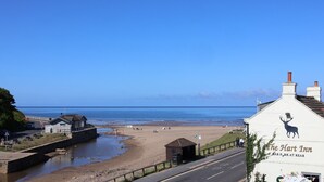 A coastal road with a beach, a river, and a building with a deer mural. - Woodbine Cottage (Whitby)