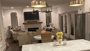 A modern kitchen with white cabinetry, a built-in microwave, and a large island with a marble countertop. - Charming 3-bedroom farmhouse with Pool &Hot Tub in Asheville Fletcher area (Fletcher)