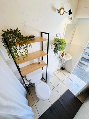 A modern bathroom with a toilet, sink, and shelves with plants. - Casa ELA Cuarta (Antigua Guatemala)
