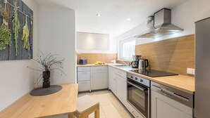 A modern kitchen with white cabinets, a wooden countertop, a built-in oven, and a stainless steel range hood. - Vacation home Strandwind near Weißenhäuser Strand a.d. Baltic Sea with garden Oldenburg/H. (Oldenburg)