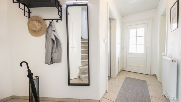 A hallway with a mirror, a coat rack, a hat, and an umbrella. - Vacation home Strandwind near Weißenhäuser Strand a.d. Baltic Sea with garden Oldenburg/H. (Oldenburg)