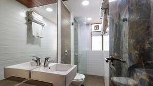 Ein Badezimmer mit einem Doppelwaschbecken, einer Toilette und einer Duschkabine aus Glas.