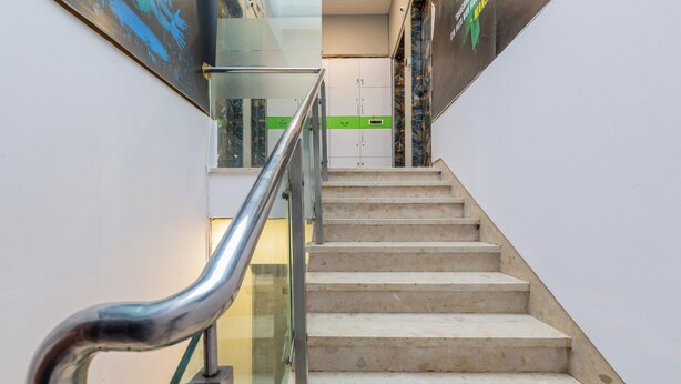 Eine Treppe mit Glasgeländer und einer grünen Schutzleiste.