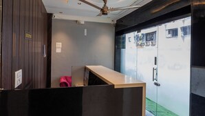 Ein Empfangsbereich mit modernem Design, inklusive einer Rezeption, Deckenventilator und Blick nach draußen durch Glastüren.