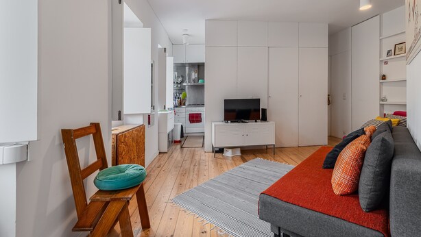 Un salon moderne avec un canapé, un téléviseur et une chaise en bois.