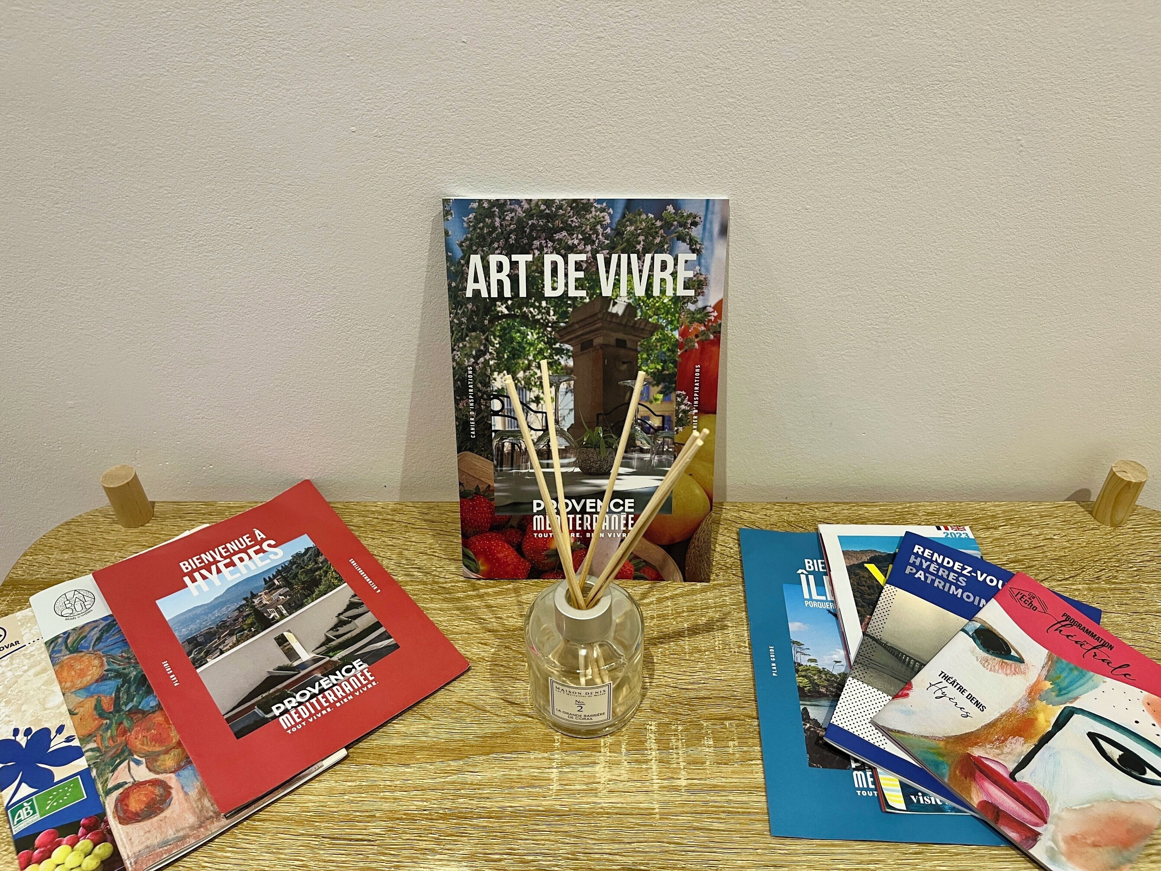 Une table avec des brochures et un bocal en verre contenant des bâtonnets de roseau.