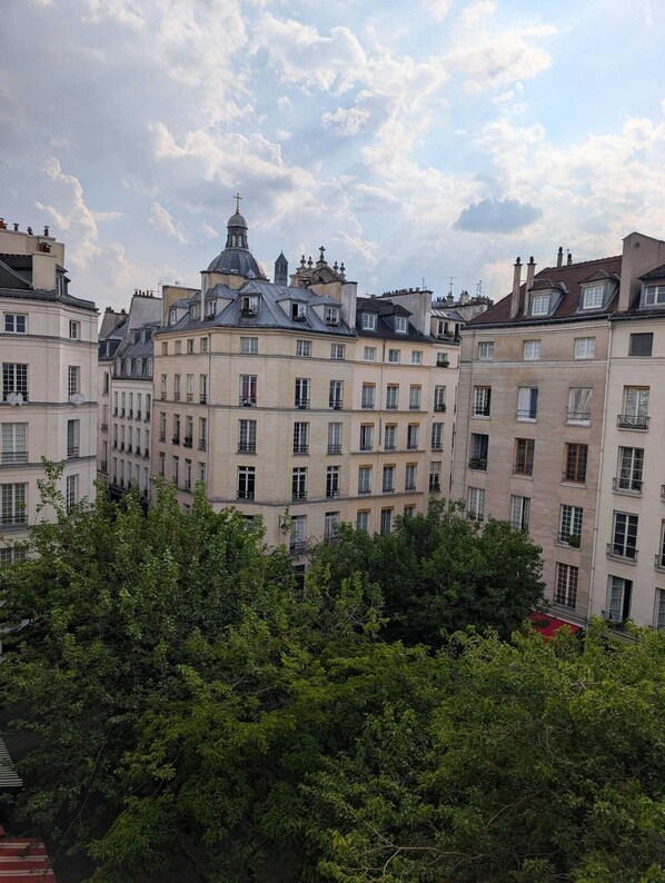 Une rangée d’immeubles à étages, tous de style architectural uniforme, avec des balcons et un bâtiment central surmonté d’un dôme et d’une croix.