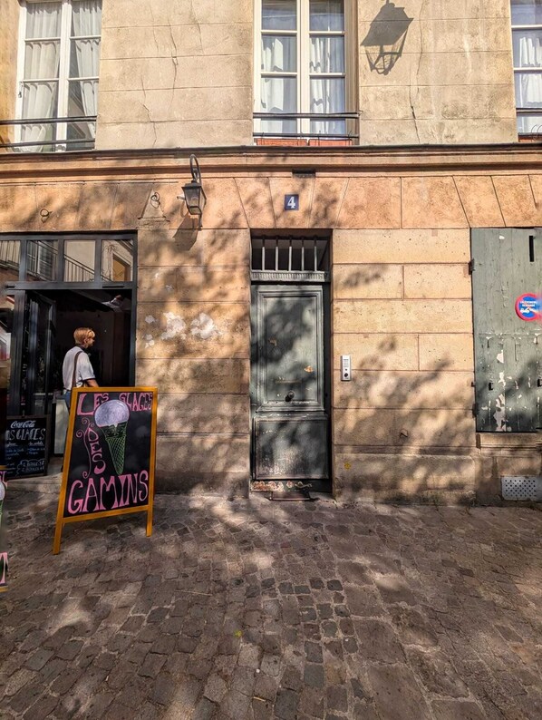 A building with a stone facade, a metal door, and a signboard advertising ice cream and games.