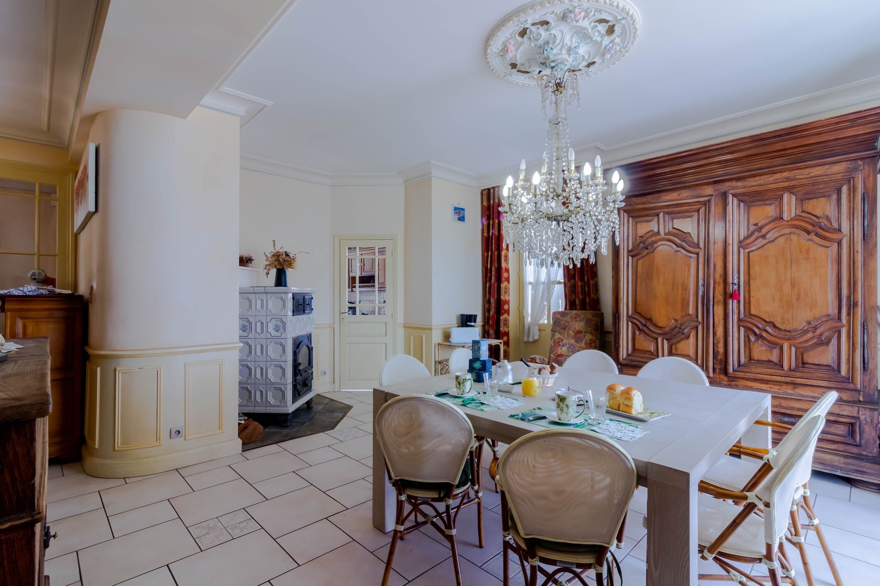 A dining area with a chandelier, wooden paneling, and a table set for four.