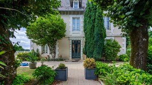 A building with a central entrance, surrounded by greenery and potted plants. - Guest Room in Vignols (Vignols)