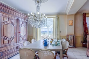 A dining area with a chandelier, wooden paneling, and a view through a large window. - Guest Room in Vignols (Vignols)