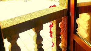 A stone balcony with a white balustrade, a stone wall, and a view of greenery and a building in the background. - A CASA DEL BOSQUE DEL AGUA+PASE A SPA PREXIGUEIRO GRATIS A PARTIR DE 01.09.2025 (MONDARIZ)