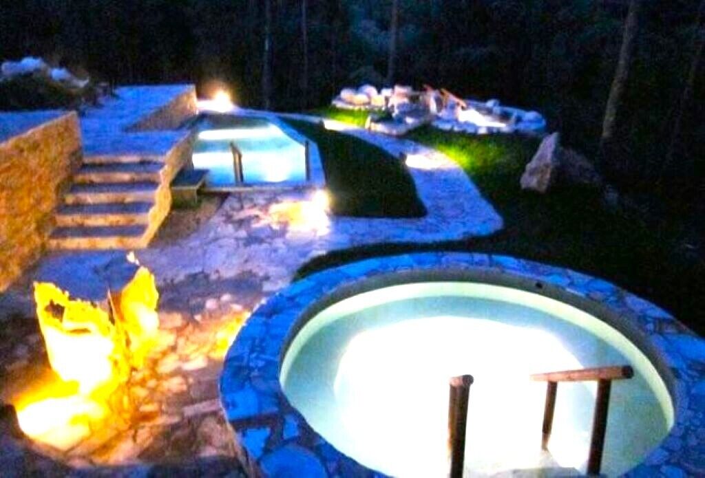 A stone pathway leading to a circular pool with a wooden bench.
