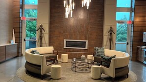 A modern lobby with a central seating area, a large TV screen, and a unique hanging light fixture. - Toast to the City/ ATL High-Rise with Bar & Views (Atlanta)