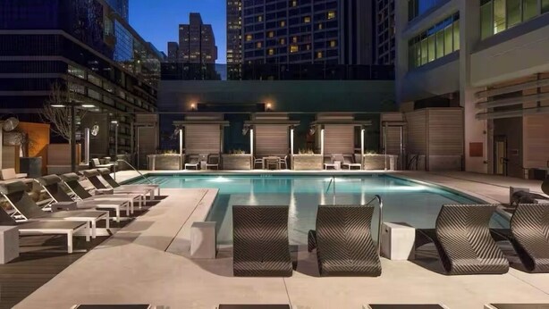 A rooftop pool area with lounge chairs and a view of the city skyline at dusk. - Toast to the City/ ATL High-Rise with Bar & Views (Atlanta)