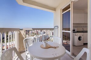 A balcony with a table and chairs, a washing machine, and a view of buildings. - Apartment 'Oura 14 A' with Shared Pool, Balcony and Wi-Fi (Armação de Pêra)