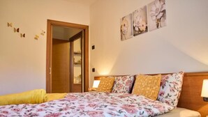 A bedroom with a floral bedspread, wooden headboard, and a door leading to another room.