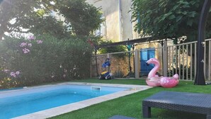 Ein Schwimmbecken mit Rutsche, umgeben von grünem Gras und Bäumen.