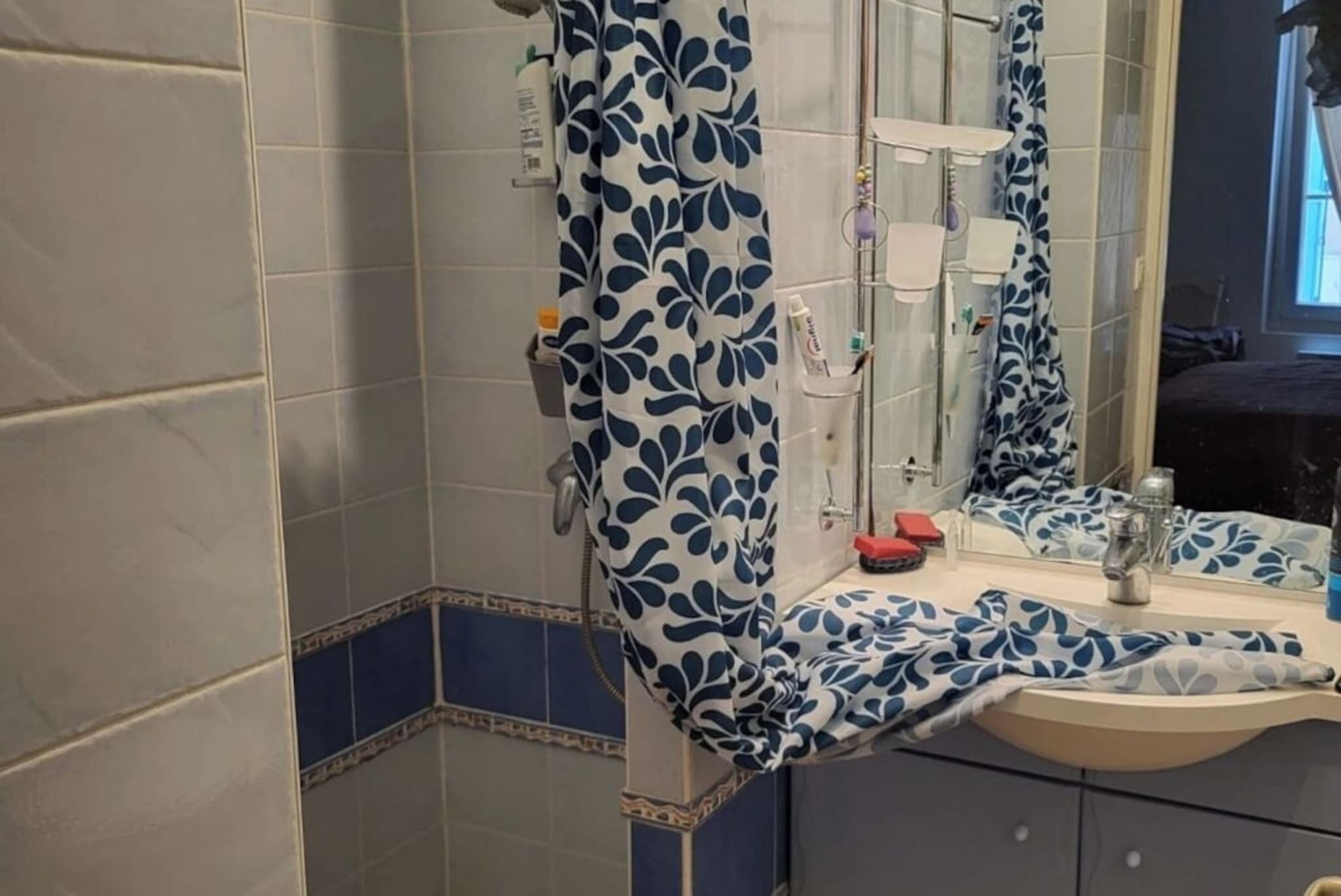 A bathroom with a sink, mirror, and shower area.