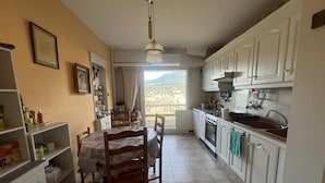 A kitchen with white cabinets, a dining table with chairs, and a view of the outdoors. - Large "classic" apartment, breathtaking view. Tennis court and swimming pool nearby. (Tresserve)