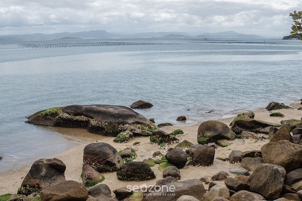 A beach with large rocks and a calm sea. - RRC - Condominium Near the Airport (Florianópolis)