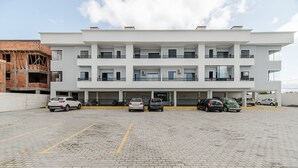 A modern multi-story building with a parking area in front.