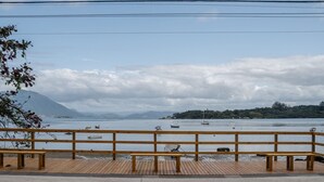 A wooden deck with benches overlooking a calm body of water with boats and a distant mountain range.