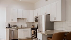 Una cocina moderna con armarios blancos, electrodomésticos de acero inoxidable y suelo de madera.