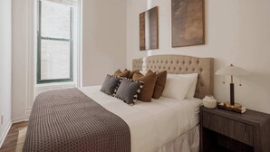 Un dormitorio con una cama grande, una mesita de noche con lámpara y dos cuadros enmarcados en la pared.