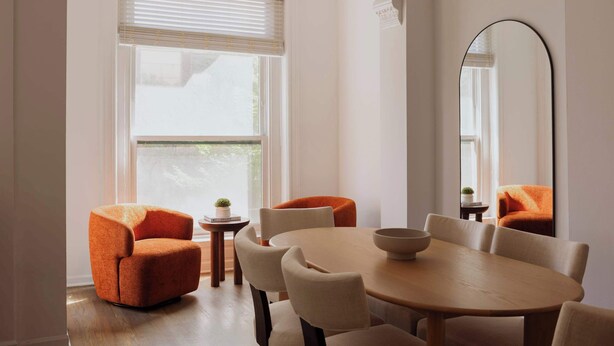 Un coin repas comprenant une table ronde, six chaises et un grand miroir.