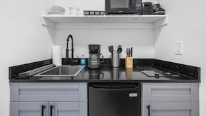 Une cuisine dotée d’un plan de travail noir, d’un four à micro-ondes, d’une machine à café et d’un lave-vaisselle.