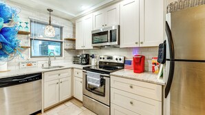 Una cucina moderna con mobili bianchi, elettrodomestici in acciaio inossidabile e lavastoviglie.