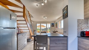 Una cocina con refrigerador integrado, escalera de madera y vistas por la puerta.