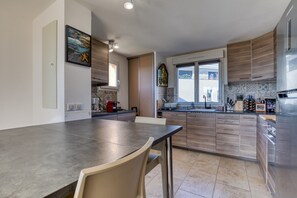 Une cuisine moderne dotée d’un grand îlot central, de meubles en bois et d’une fenêtre laissant entrer la lumière naturelle.